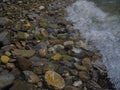 Wet sea stones on the coast are washed by a wave